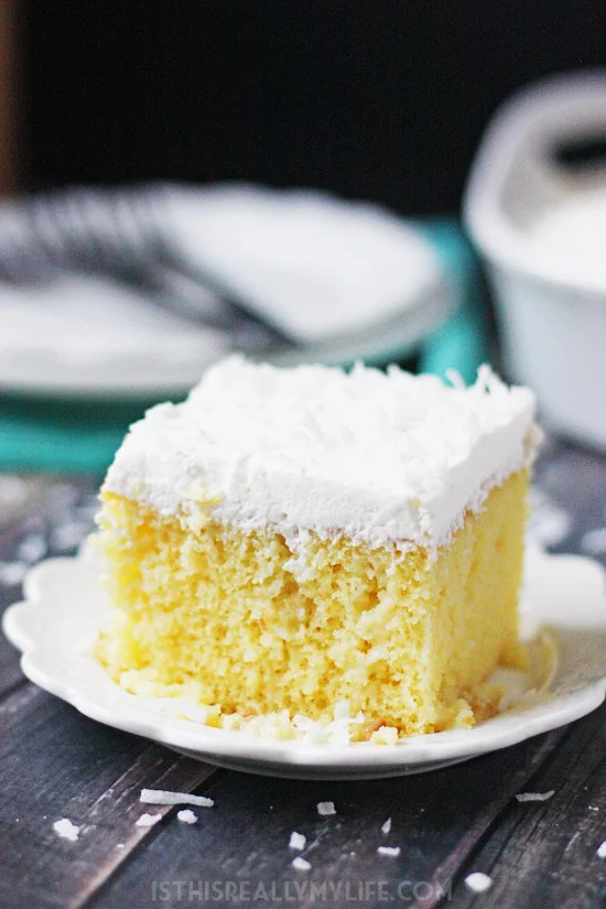 Coconut Poke Cake -- This coconut poke cake features a yellow cake infused with sweet coconut cream and topped with homemade whipped cream frosting and shredded coconut.