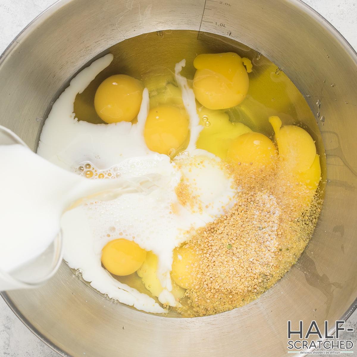 Adding milk in a bowl with eggs and mustard