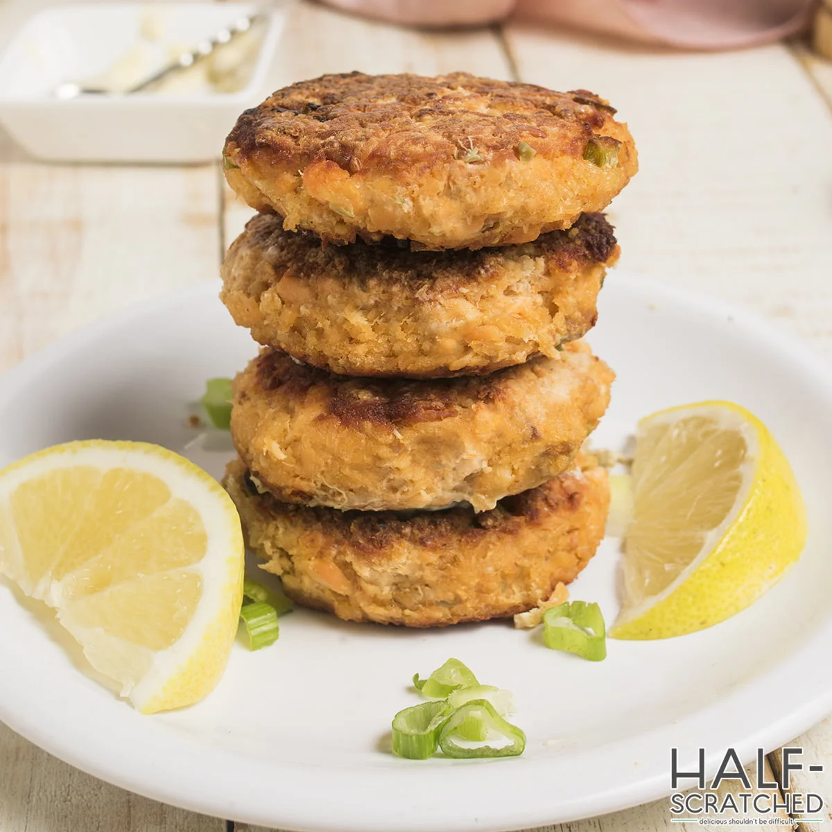 Four Salmon Patties in a plate with lemon slices