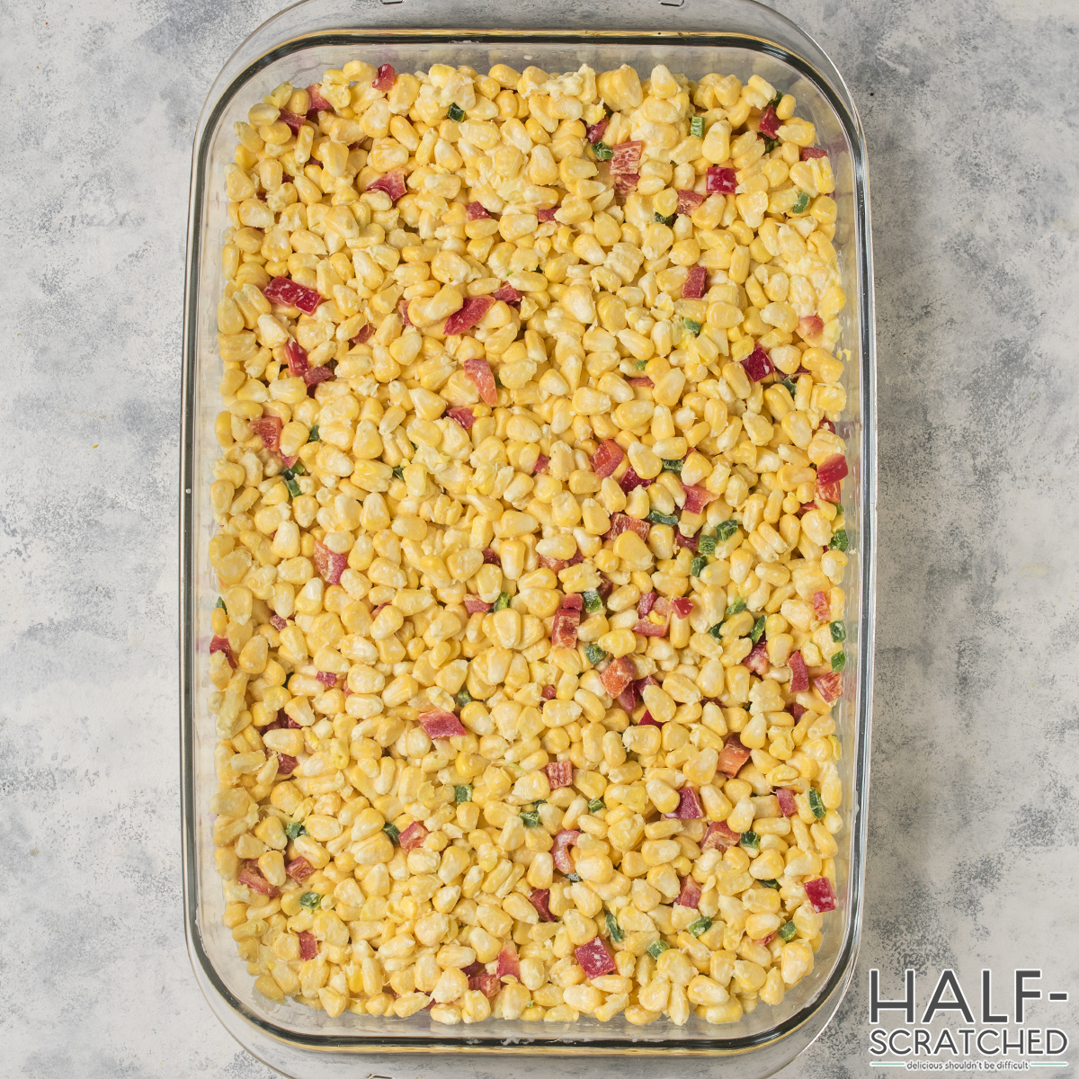 Corn casserole in a 9x13 baking dish with red bell peppers and jalapenos