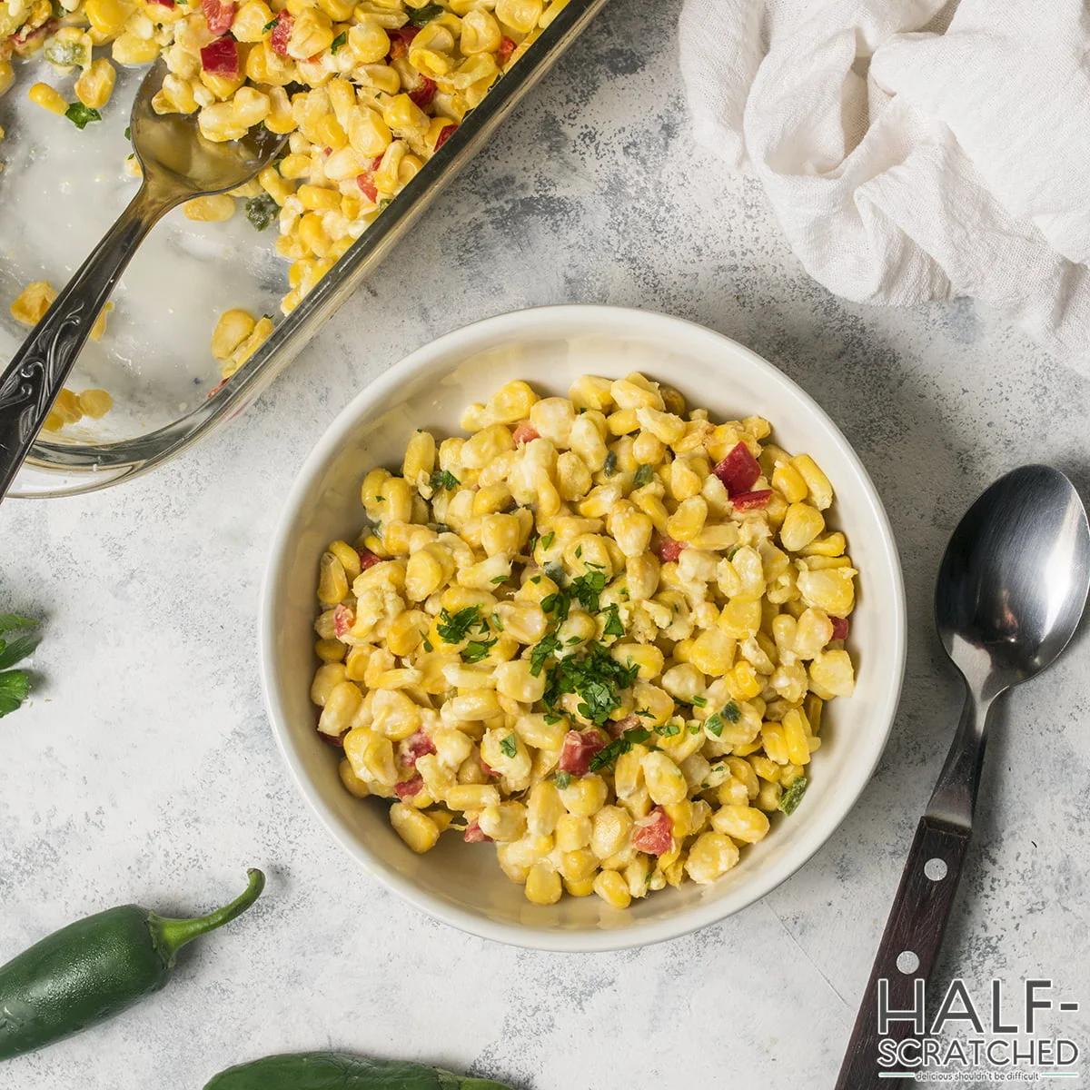 Top view of corn casserole in a white bowl garnished with parsley