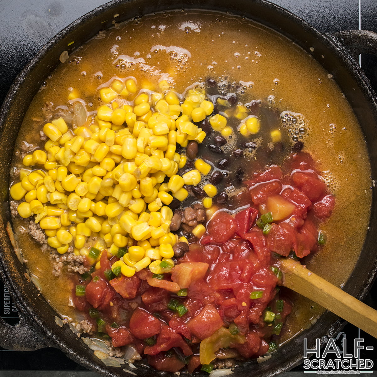 Ingredients including corn, beans, and tomatoes in a pot for taco soup