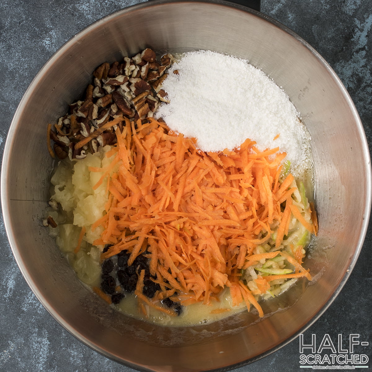 Wet ingredients mixed with carrots, pineapple, and pecans in a bowl