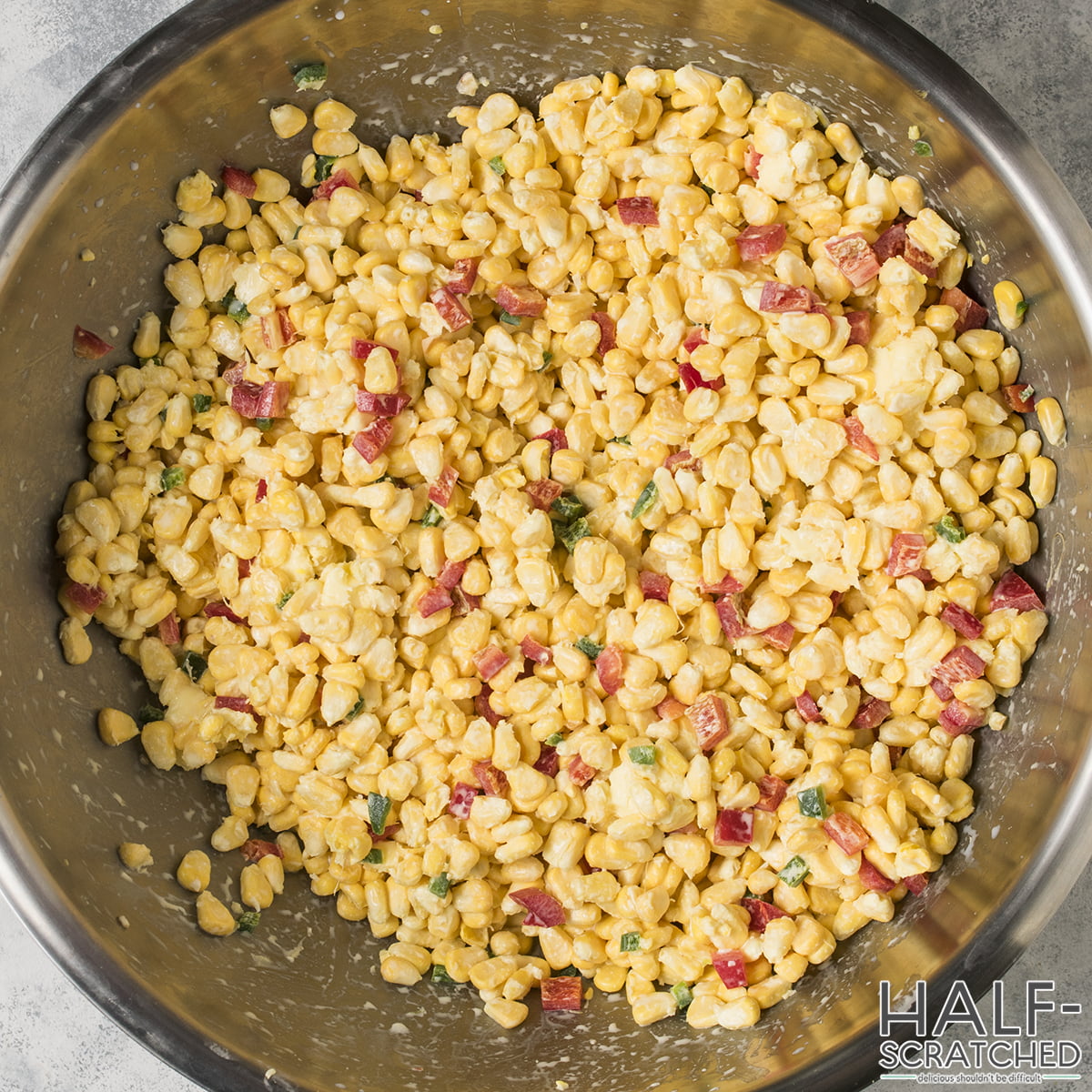 Corn, red bell peppers, jalapenos, and heavy cream mixed in a bowl