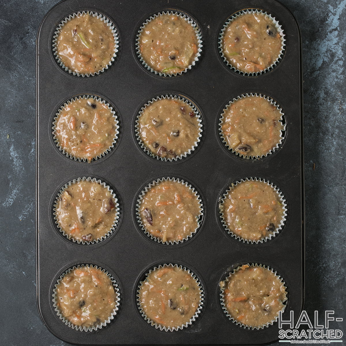 Muffin batter portioned into lined muffin cups in a baking tray