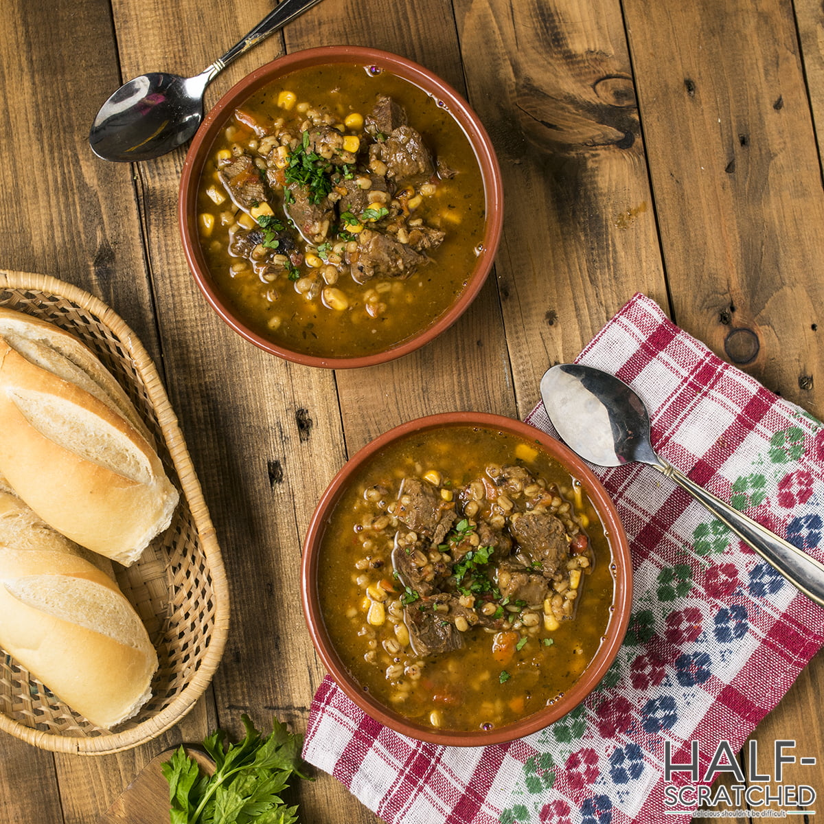 Two bowls of beef and barley soup served with bread
