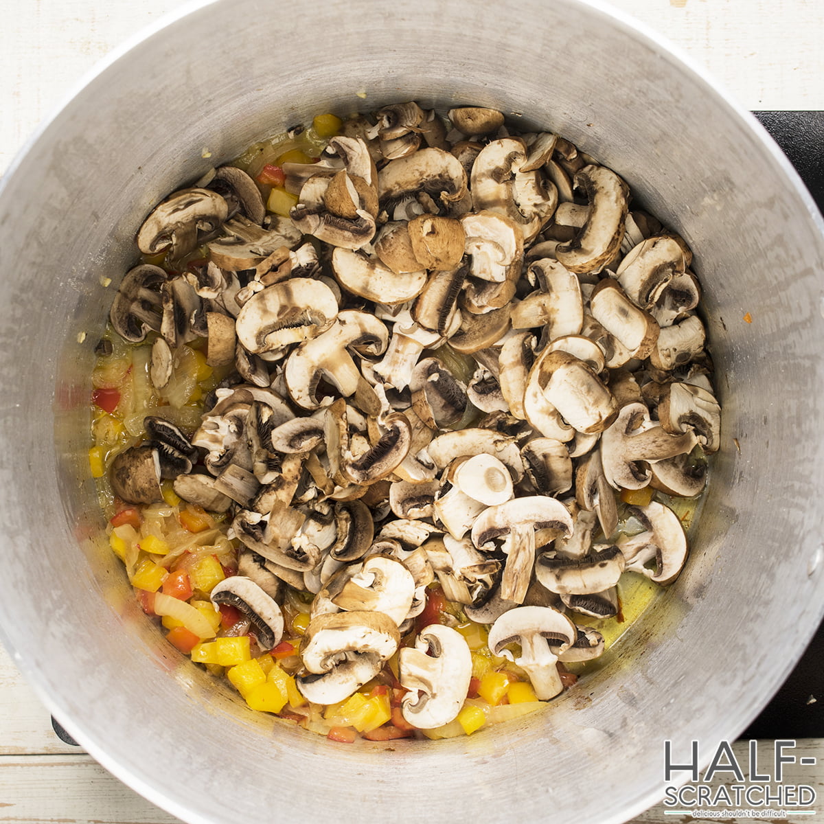 Mushrooms and bell peppers cooking in a pot