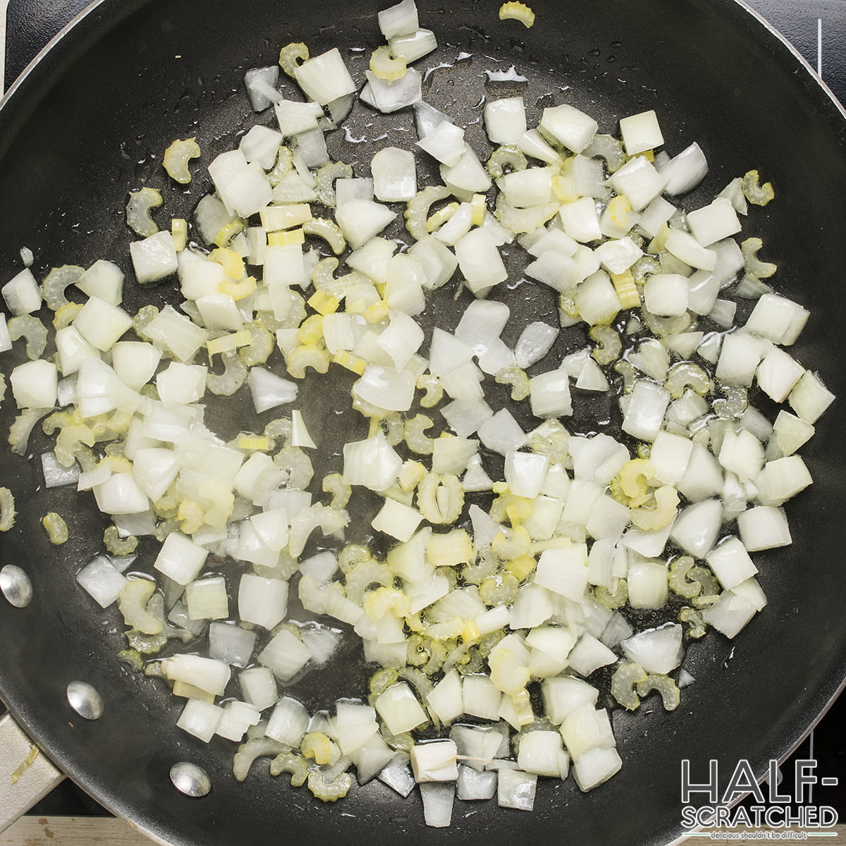 Onions and celery sautéing in a skillet